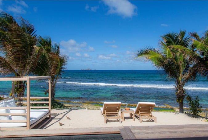 Beachfront lounge area at Villa K in Anse des Cayes with daybed and ocean views.