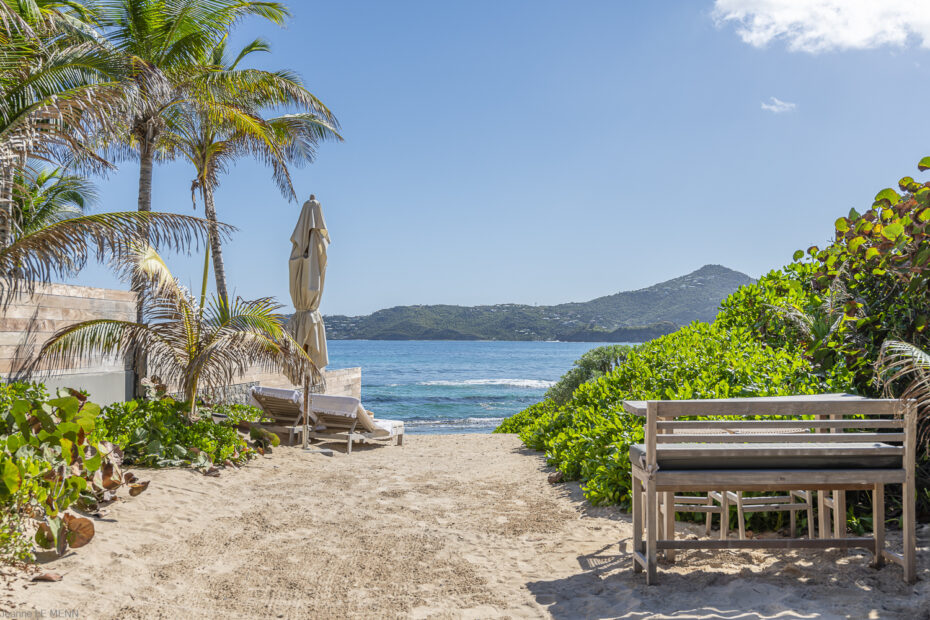 Beachfront lounge area at Villa K with daybeds and palm trees overlooking Anse des Cayes.